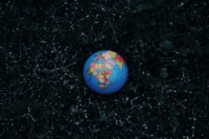 Top view of small colorful Earth globe toy placed on dark grass in nature